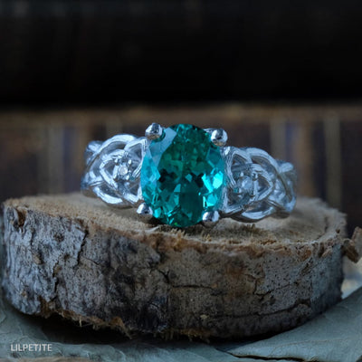 celtic knot engagement ring set with oval green emerald and made of platinum.