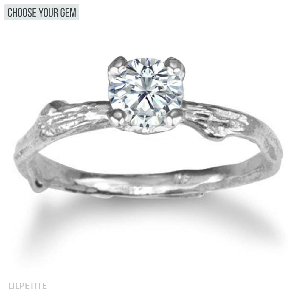 A 14k gold ring with a textured band of a twig and a central gemstone in a four-prong setting.